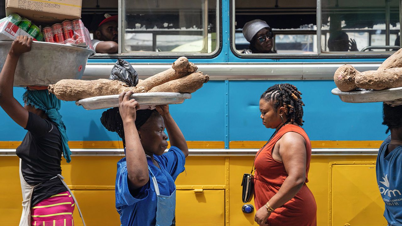 Street vendors pass a stationary bus in the Makola district of Accra, Ghana.