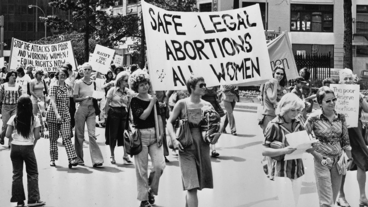 A black and white photograph of women marching carrying a banner which reads 'Safe Legal Abortions for All Women' at a pro-choice demonstration in New York City, USA in 1978.