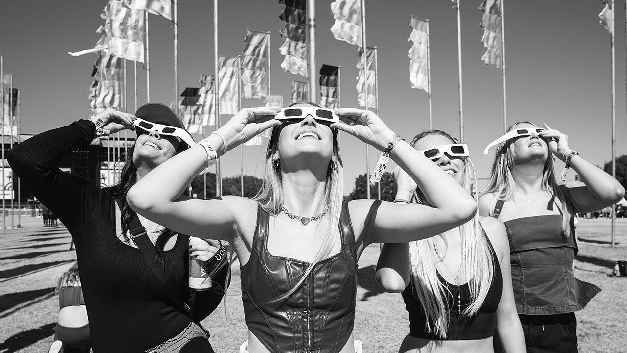 Festival goers watch the solar eclipse through glasses.